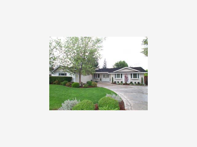 A large white house with a driveway and lawn.