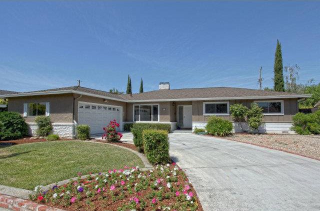 A house with a driveway and flowers in the front yard.