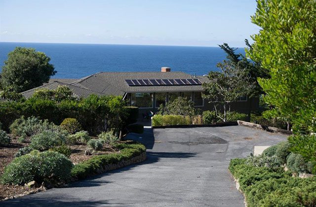 A house with a view of the ocean and a driveway.