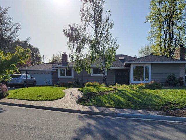 A house with a driveway and trees in the background.