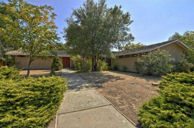 A large driveway with bushes and trees in front of it.