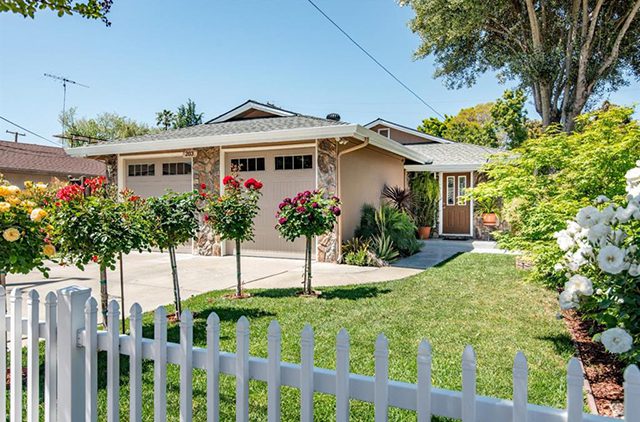 A house with a white picket fence and trees.