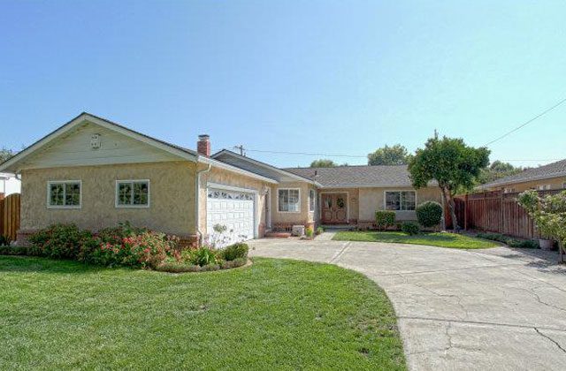 A house with a driveway and lawn in front of it.