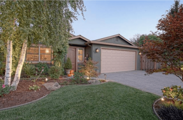 A house with a driveway and lawn in front of it.