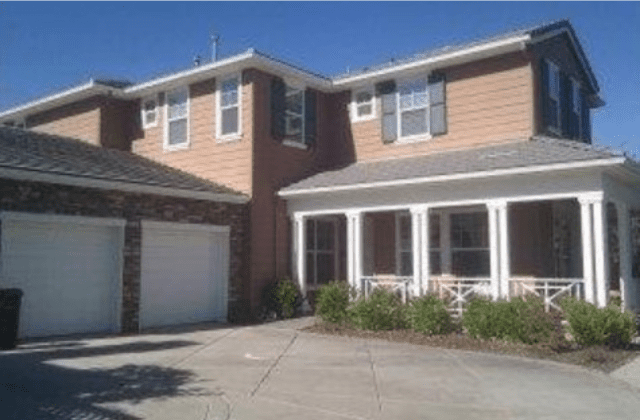 A large house with two garage doors and a driveway.