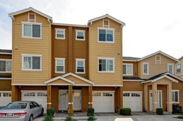 A row of houses with garage doors and car parked in front.