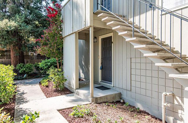 A white building with stairs leading to the front door.