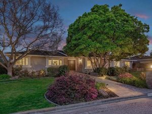 A house with a garden and trees in the front yard.