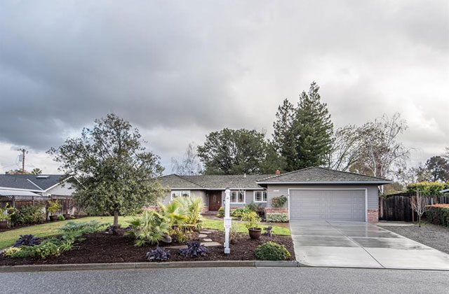 A house with a driveway and trees in the background