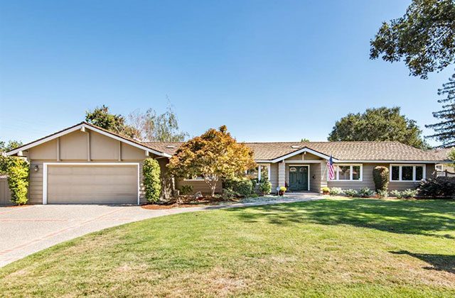 A large house with a driveway and lawn.