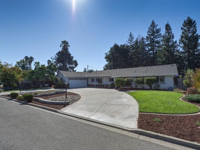 A large driveway with a house and trees in the background.