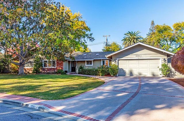 A house with a driveway and trees in the background.