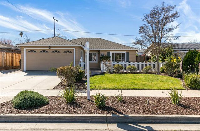 A house with a driveway and a fence in front of it.